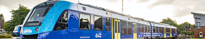 Türkis-blau-gelb-weiser Wasserstoffzug mit Logo der evb (Eisenbahnen und Verkehrsbetriebe Elbe Weser) von rechts nach links fahrend